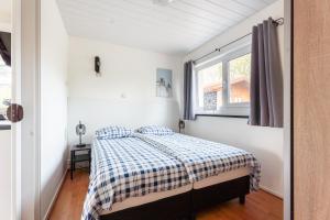 a bedroom with a bed with a checkered blanket at Zonneschijn, bungalow op vakantiepark bij zee in Baarland