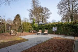 two chairs sitting on a patio in a garden at Zonneschijn, bungalow op vakantiepark bij zee in Baarland