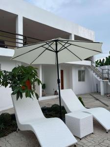 two white chairs and an umbrella on a patio at Casa de Matilda in Silang