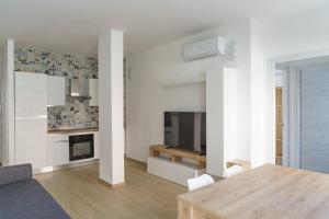 a white living room with a table and a television at Costa d'Abruzzo - Casa Vacanza in Montesilvano