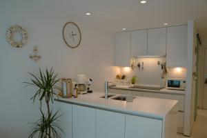 a kitchen with white cabinets and a clock on the wall at The White coast studio in Nieuwpoort +24 photos