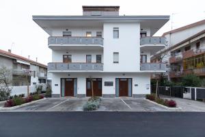 a white building with brown doors in a parking lot at Costa d'Abruzzo - Casa Vacanza in Montesilvano