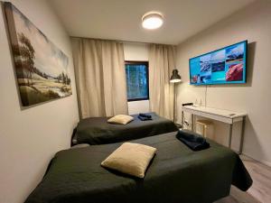 a room with two beds and a desk and a tv at Modern studio apartment with free parking in Kuopio