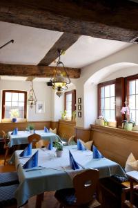 un restaurante con mesas y sillas azules y ventanas en Landhaus Zum Falken en Tauberzell