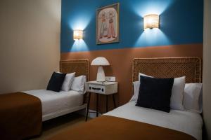 two beds in a room with blue walls and lights at Casa Lombarda in Mérida