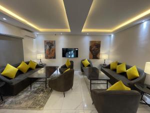 ein Wohnzimmer mit Sofas, einem Tisch und gelben Kissen in der Unterkunft Ringruby Hotel, Oladipo Bateye in Lagos