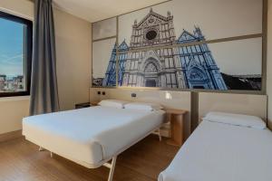 zwei Betten in einem Zimmer mit einem Bild einer Kirche in der Unterkunft B&B Hotel Firenze Novoli in Florenz