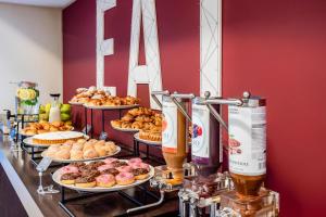 Ein Buffet mit Tellern voller Donuts und Getränken auf einer Theke in der Unterkunft B&B Hotel Firenze Novoli in Florenz