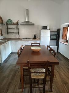a kitchen with a wooden table with chairs and a bowl on it at La casa di Nonna Carta in Fordongianus