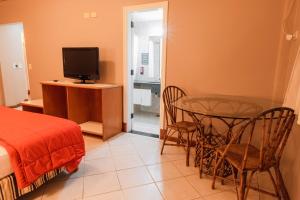 a bedroom with a bed and a table and a television at Marcopolo Suites Iguazu in Puerto Iguazú