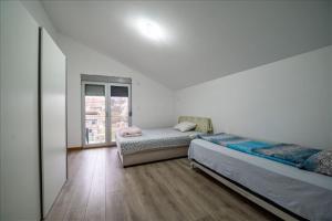 a white room with two beds and a window at Super Vila in Jajinci