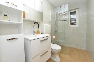a white bathroom with a toilet and a shower at Robinson Luminara in Vrbanj