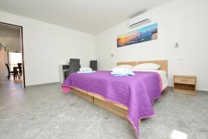 a bedroom with a bed with a purple blanket on it at Robinson Luminara in Vrbanj