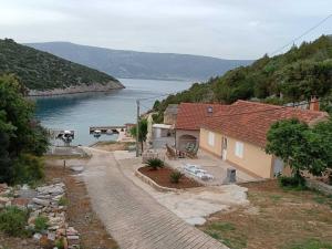 a house on a hill next to a body of water at Robinson Luminara in Vrbanj
