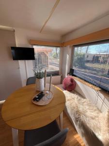 a living room with a wooden table and a couch at Prachtige stacaravan met heerlijke overkapping in Eext