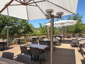 a patio with tables and chairs and an umbrella at Camping Le Soleil du Verdon in Esparron-de-Verdon