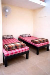 two twin beds sitting in a room with a red and brown at Vishram Yatri Niwas in Kolhapur