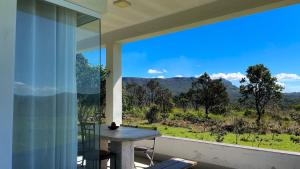 a room with a large window with a table and a view at Mirante do Morro in Alto Paraíso de Goiás