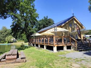 a large building with tables and umbrellas next to a lake at u koupaliste in Mimoň