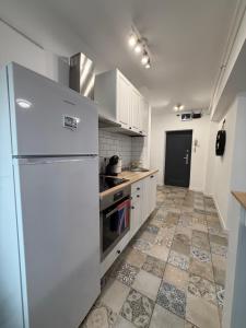 a kitchen with a white refrigerator and a tile floor at Central Studio Yoko , Craiova in Craiova