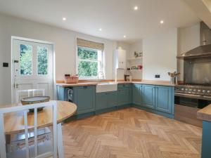 a kitchen with blue cabinets and a wooden floor at Rectory Cottage in Alton
