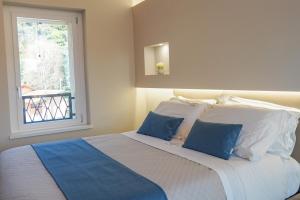 a bedroom with a bed with blue pillows and a window at Gio Leo Guest House in Lesa