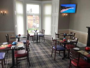 a restaurant with tables and chairs and a flat screen tv at Edenbank Hotel in Dumfries