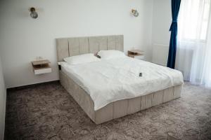 a bedroom with a large bed with white sheets and pillows at Armonia -Rucar in Podu Dîmboviţei +14 photos