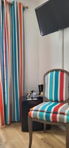 a living room with a chair and a television at Hôtel Ursula in Cambo-les-Bains