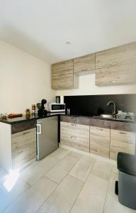 eine Küche mit Holzschränken und einem Edelstahlkühlschrank in der Unterkunft Studio El Canigou in Prades