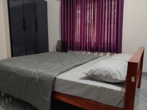 a bed in a bedroom with a purple curtain at Little Eden in Cochin