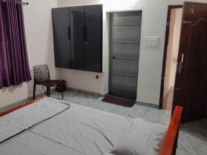 a bedroom with a bed and a tv and a chair at Little Eden in Cochin