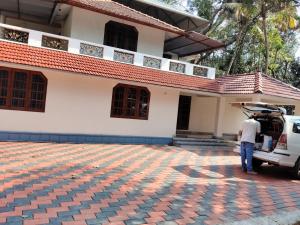 a man standing in front of a house with his car at Little Eden in Cochin