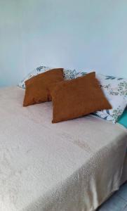 a bed with three pillows on top of it at Praticidade e conforto á poucos passos do aereoporto in Várzea Grande