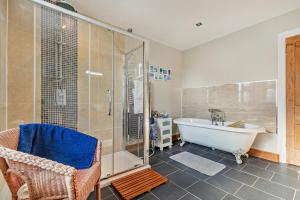 a bathroom with a tub and a shower and a chair at 3 Bed in Uphill oc-n27747 in Linkinhorne +22 photos