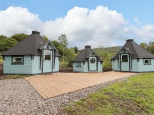 two houses with a wooden deck in a field at Little Luxe Lodges 2 in Balmacara
