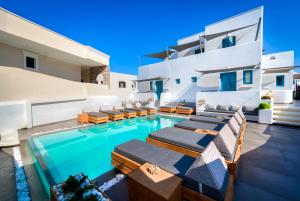 ein Pool mit Chaiselongue und ein Haus in der Unterkunft Evgenia Villas & Suites by Calm Collection in Fira