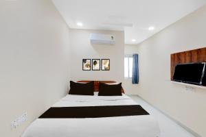 a white room with a bed and a flat screen tv at Hotel O RB Delight in Karīmnagar +21 photos