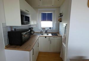a small kitchen with a sink and a microwave at Tief 10 Austernfischer 708 in Wangerland