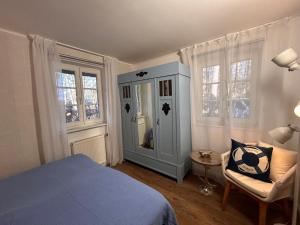 a bedroom with a bed and a chair and windows at Achtern Diek Haus 12d Wohnung 1 PALSTEK in Müggenburg