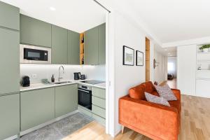 a kitchen with green cabinets and an orange couch at GuestReady - Menéres Apartments in Matosinhos