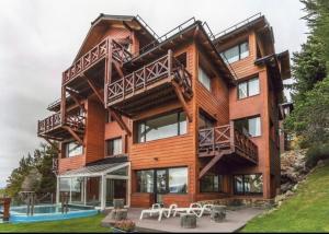 a large wooden house with a pool in front of it at Catalonia Sur Aparts in San Carlos de Bariloche