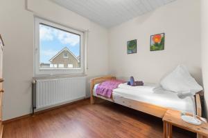 a small bedroom with a bed and a window at Watt'n Mehr in Krummhörn