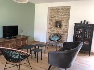 a living room with a couch and chairs and a tv at Entre terre et mer in Ploemeur