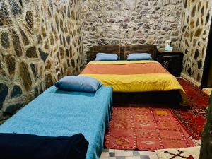 two beds in a room with a stone wall at riad imlil in Imlil