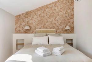 a bedroom with a white bed with towels on it at La Maison Léoncine in Allonnes