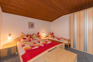 a bedroom with two beds with red and yellow pillows at Hinterbichlhof - Apartments in Viehhofen