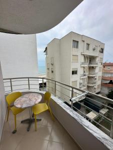 a balcony with two chairs and a table and a building at Mesdheu ApartHotel in Durrës