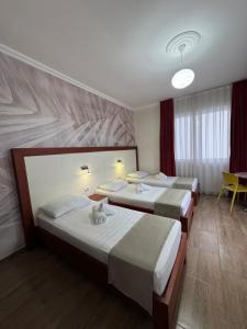 a hotel room with three beds and a table at Mesdheu ApartHotel in Durrës