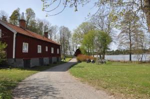 a path next to a red barn next to a lake at The Gardener House - Grönsöö Palace Garden in Grönsöö